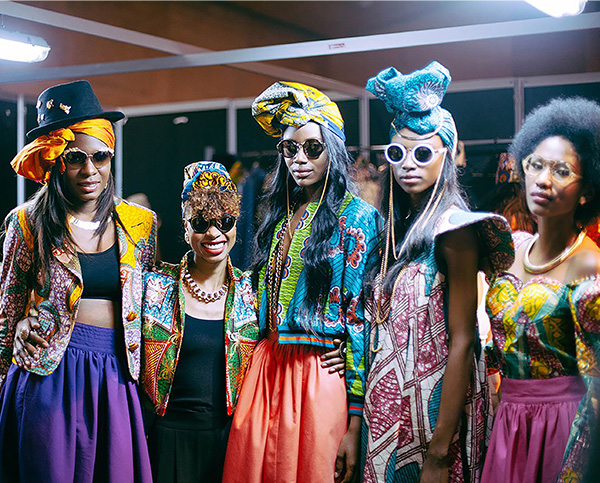 five Black models in brightly colored fashions look into the camera