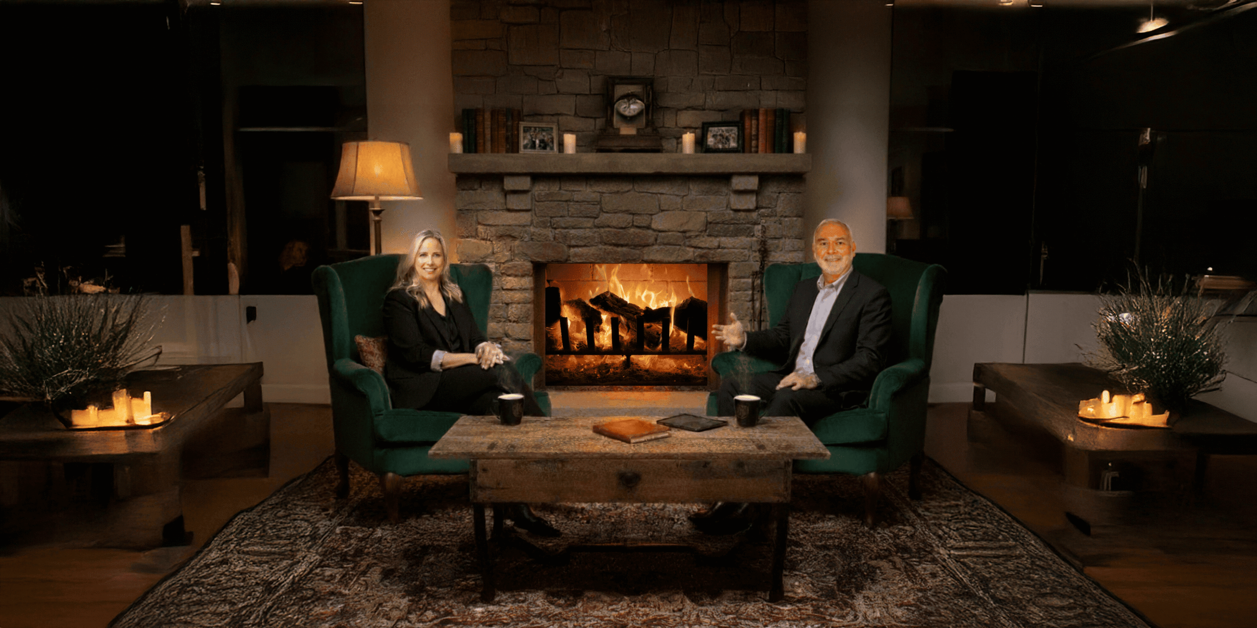 Sarah Clarke and David Uricoli sit in front of a fireplace