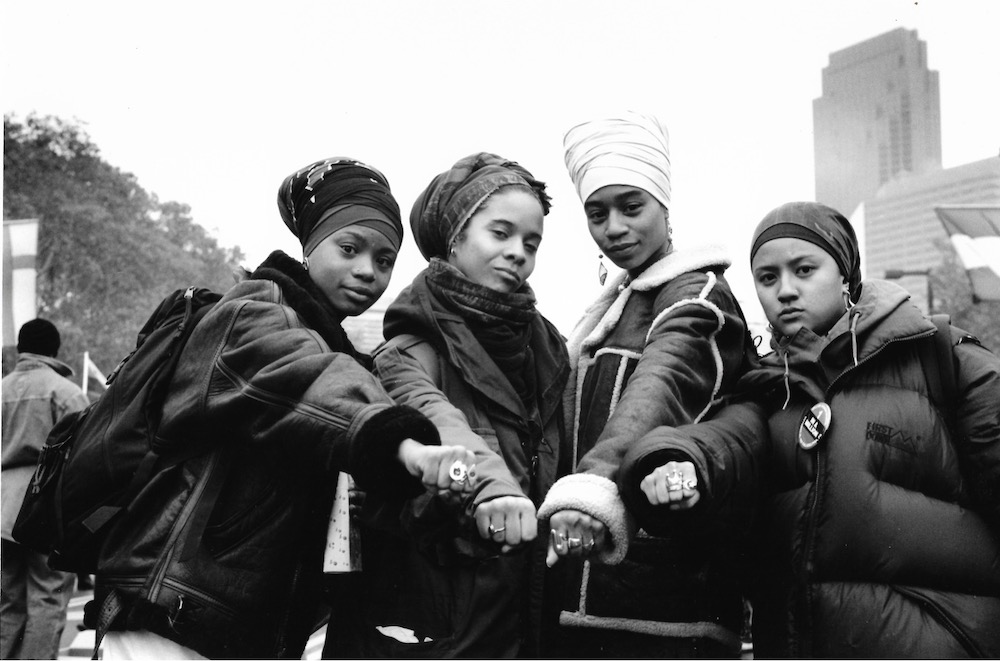 four women with fists joined together as a group
