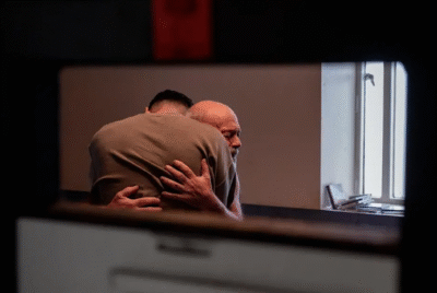 two men embracing near a window
