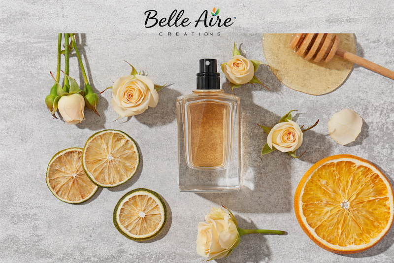 perfume bottle, slices of citrus, honey, rosebuds, and Belle Aire logo